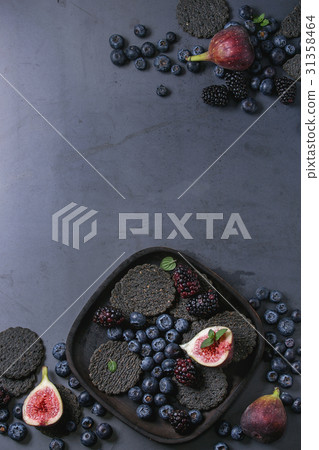 Variety of berries and figs with black crackers Variety of berries and figs with black crackers 31358464