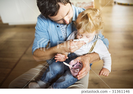 Young father at home feeding his little son with Young father at home feeding his little son with 31361146