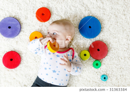 Cute baby girl playing with colorful wooden rattle 31363384