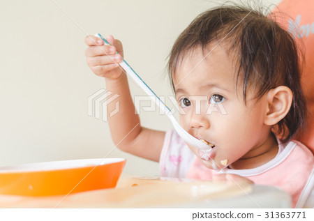 Asian toddler girl eating cereals with milk. Asian toddler girl eating cereals with milk. 31363771