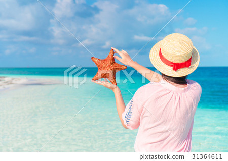 Young girl in hat holding giant red starfish on Young girl in hat holding giant red starfish on 31364611