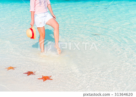 Female feet on white sandy beach. Starfish on the 31364620