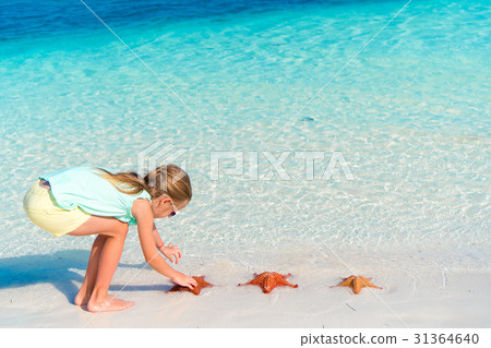 Adorable little girl holding giant red starfish on 31364640