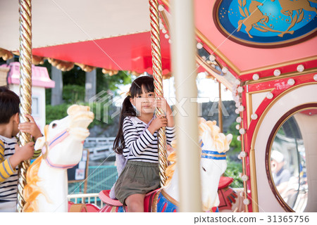 A girl riding a merry-go-round A girl riding a merry-go-round 31365756