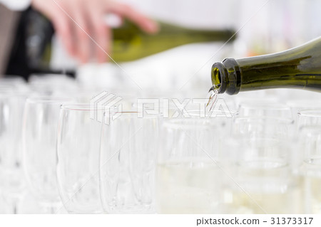Waiter pours champagne in glasses 31373317