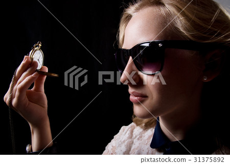 The girl in dark glasses holding a watch  31375892