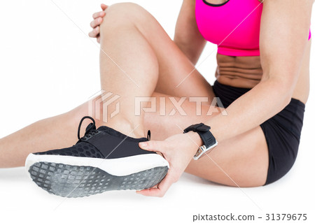 Female athlete sitting and removing her shoe 31379675