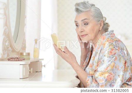 Senior woman applying makeup Senior woman applying makeup 31382005