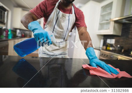 Mid section man cleaning marble counter in kitchen Mid section man cleaning marble counter in kitchen 31382986