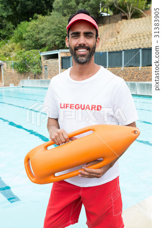 Lifeguard standing with rescue buoy near poolside Lifeguard standing with rescue buoy near poolside 31383905