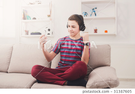 Teenage boy enjoying music in headphones at home Teenage boy enjoying music in headphones at home 31387605