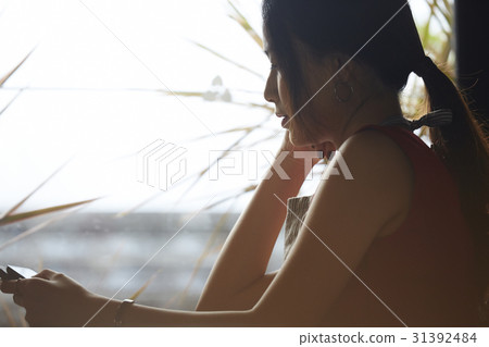 a portrait of a woman with tablet sitting nearby window. a portrait of a woman with tablet sitting nearby window. 31392484