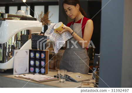 a woman is standing and cleaning a cup very carefully. a woman is standing and cleaning a cup very carefully. 31392497