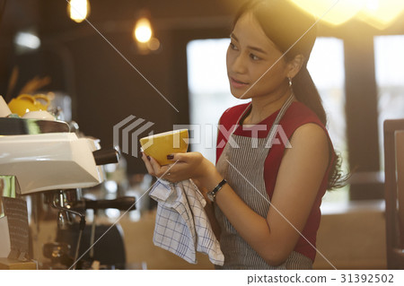 a woman is looking something when holding a cup. a woman is looking something when holding a cup. 31392502