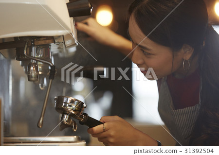 a woman is checking and setting up a coffee machine. 31392504