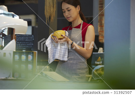 a woman is cleaning a cup before opening hours. 31392507