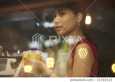 a staff of café is cleaning a cup when she thinks something. a staff of café is cleaning a cup when she thinks something. 31392522