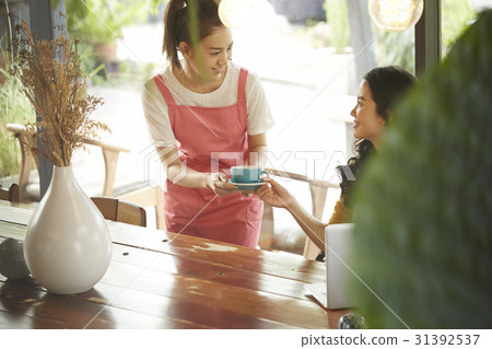 A waitress is giving a cup of coffee to a customer. A waitress is giving a cup of coffee to a customer. 31392537