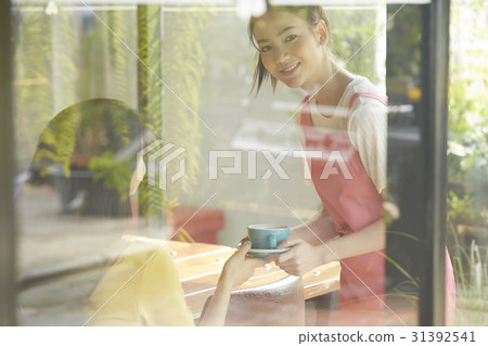 a waitress is serving drink for customer when she looks outside. 31392541