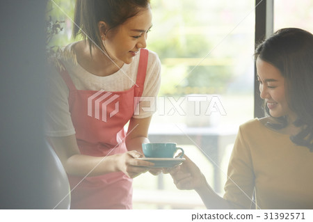 Cheerful waitress is giving coffee to a customer at the cafeteria. 31392571