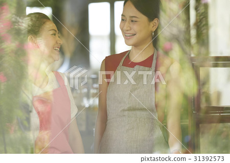 The female staffs are chatting and smiling in the café. 31392573