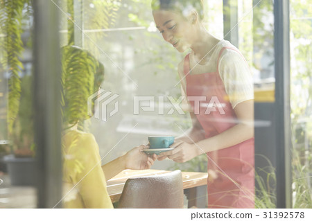 A waitress is giving a coffee to customer, view through the window. A waitress is giving a coffee to customer, view through the window. 31392578