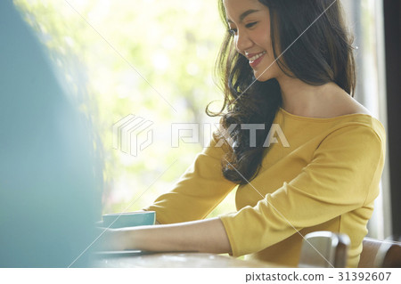 Young woman is smiling and sitting in the cafeteria. Young woman is smiling and sitting in the cafeteria. 31392607