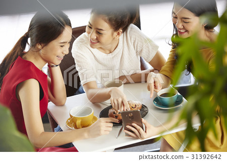 Female colleagues are discussing something funny in smartphone. Female colleagues are discussing something funny in smartphone. 31392642