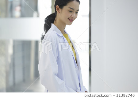 young female doctor is smiling and looking down. young female doctor is smiling and looking down. 31392746