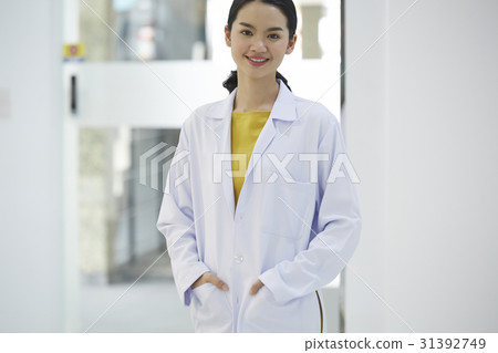 Portrait of young female doctor standing and smiling Portrait of young female doctor standing and smiling 31392749