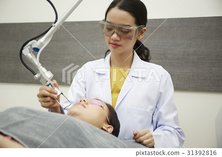 A photo of female doctor doing a facial treatment by laser. A photo of female doctor doing a facial treatment by laser. 31392816