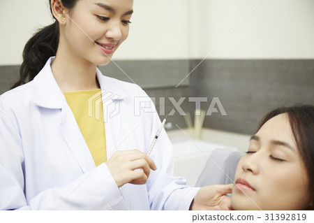 A female doctor is ready to inject something into a girl's face. 31392819