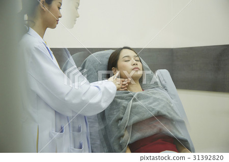 A female doctor is injecting something into a girl's face lying. 31392820