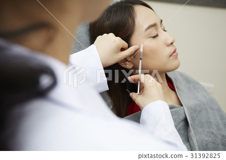 A photo of someone injecting botox into woman's face. 31392825