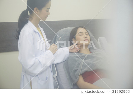 A doctor is preparing to inject medicine into a girl's face 31392903