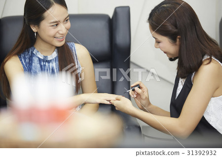 a happy girl is painted nails by a woman in nail salon 31392932