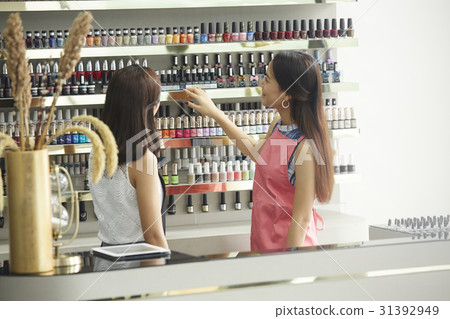 two girls are looking at a shelf of nail polish bottles two girls are looking at a shelf of nail polish bottles 31392949