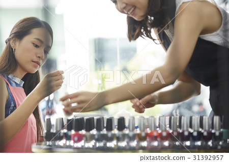 the female staffs are sorting the nail polish bottles. 31392957