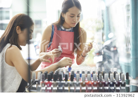 two girls are sorting the colors of the nail polish bottles 31392962