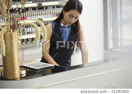 The female staff is working inside a nail supply store. 31392969
