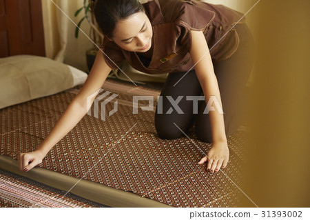 a woman is arranging a mattress for spa 31393002