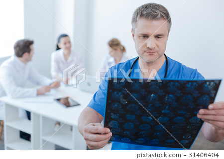 Serious neurologist examining mrt scan photo at Serious neurologist examining mrt scan photo at 31406404