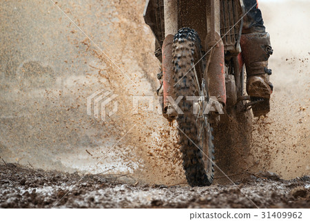 Motocross driver splashing mud on wet and muddy  31409962