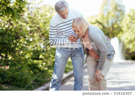 Caring pensioner helping senior wife outdoors 31410307