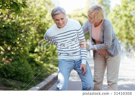 Patient old woman taking care of ill man outdoors Patient old woman taking care of ill man outdoors 31410308