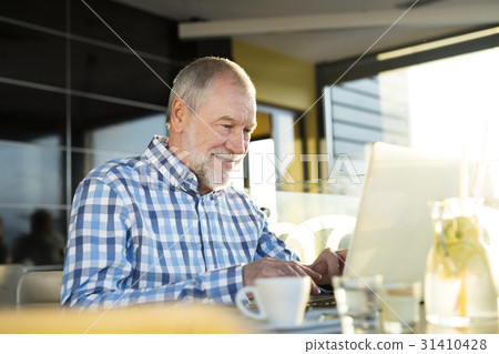 Senior businessman working on laptop in cafe Senior businessman working on laptop in cafe 31410428