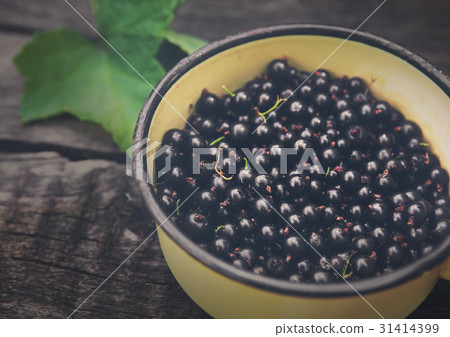 Black currants pot closeup on rustic wood 31414399