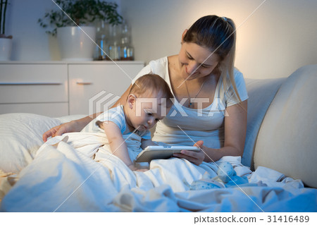 Baby boy sitting on bed with mother 31416489