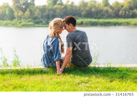 Young love couple sitting on the river bank in Young love couple sitting on the river bank in 31416765