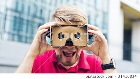 Funny man using cardboard virtual reality goggle Funny man using cardboard virtual reality goggle 31416834